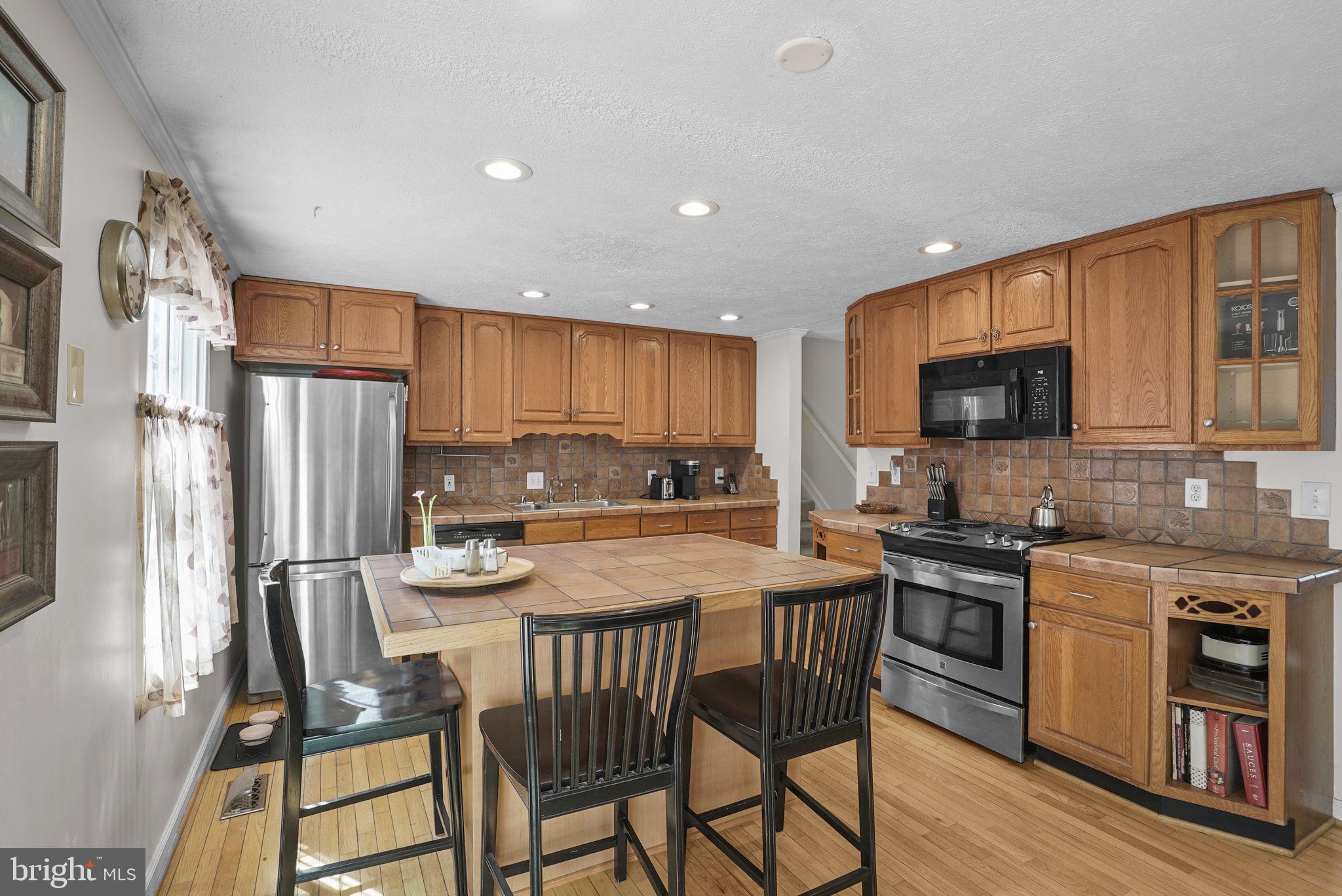 7129 Banjo Court Columbia, MD 21045 - Photo 4 of 46 a kitchen with stainless steel appliances granite countertop a stove a refrigerator a sink a stove a dining table and chairs with wooden floor