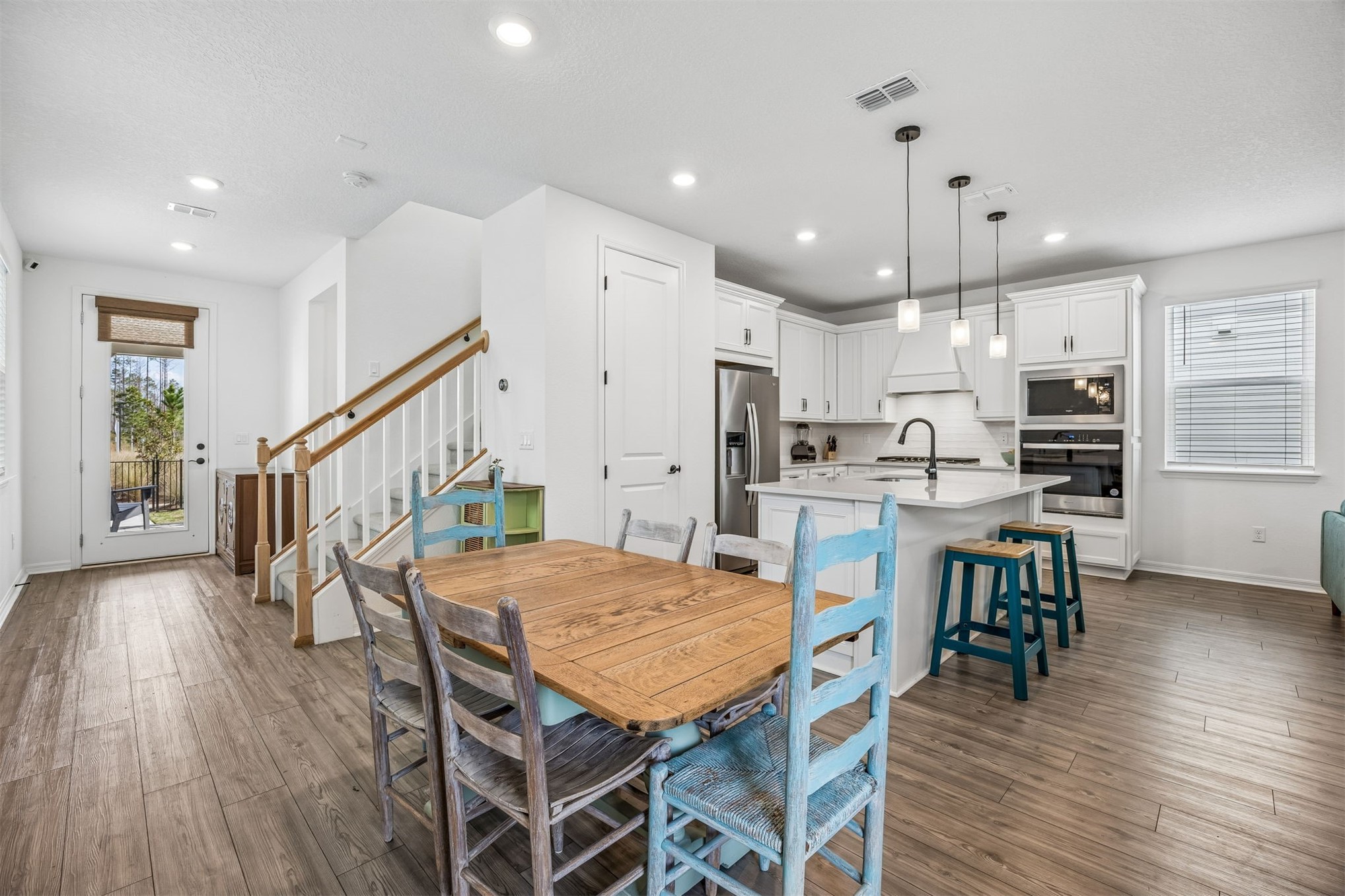 236 Hawthorn Park Circle Yulee, FL 32097 - Photo 6 of 28 a dining room with stainless steel appliances kitchen island granite countertop a table chairs and a wooden floor