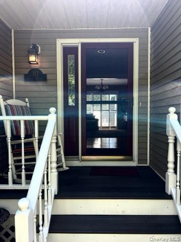 312 Riley Avenue Calverton, NY 11933 - Photo 4 of 30 Welcoming front porch featuring a dark wood-finish deck, white baluster railings, and a dark-paneled entry door with sidelights