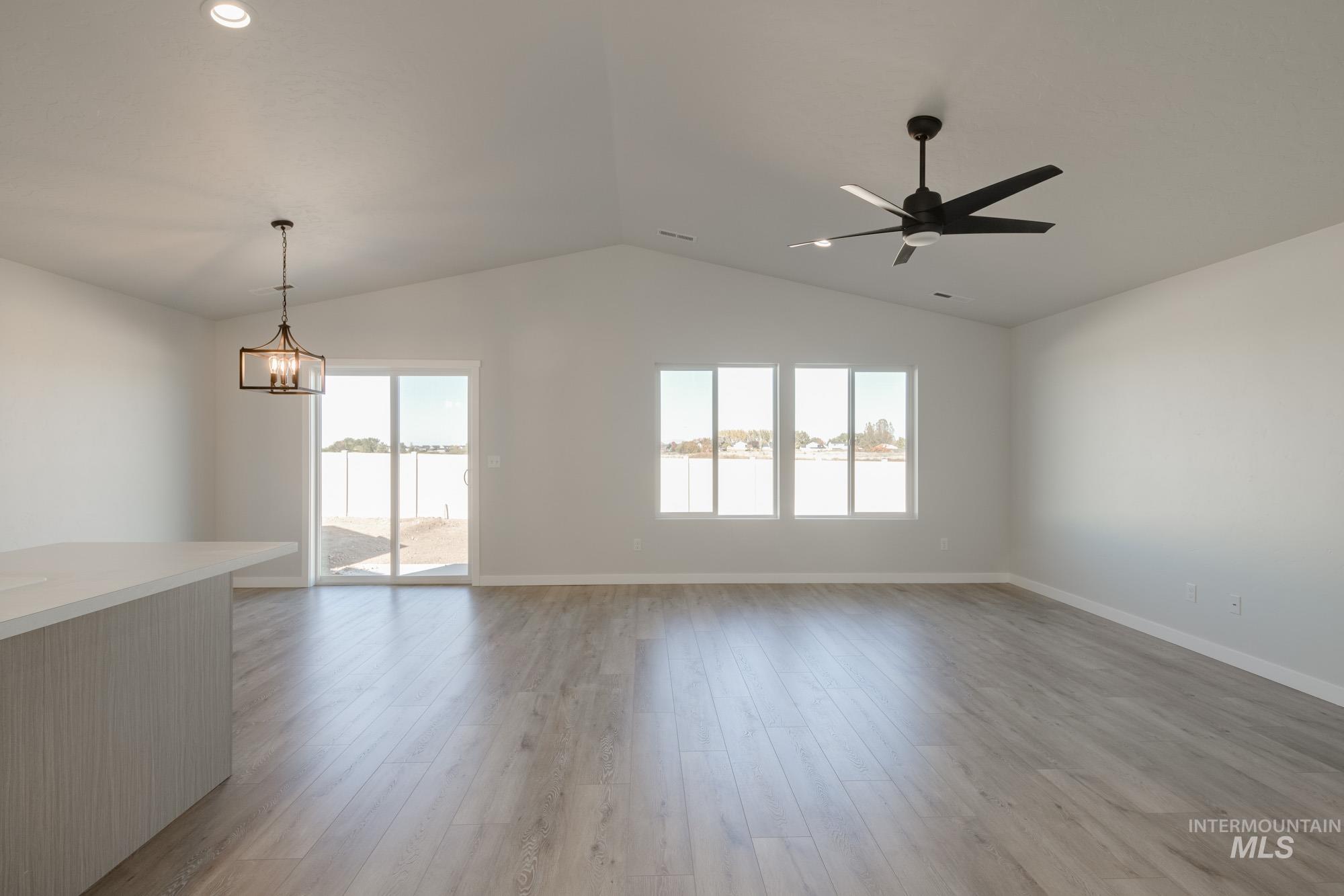 1832 West Unforgettable Street Meridian, ID 83642 - Photo 10 of 22 Unfurnished living room with a water view, light wood-type flooring, vaulted ceiling, recessed lighting, and a chandelier