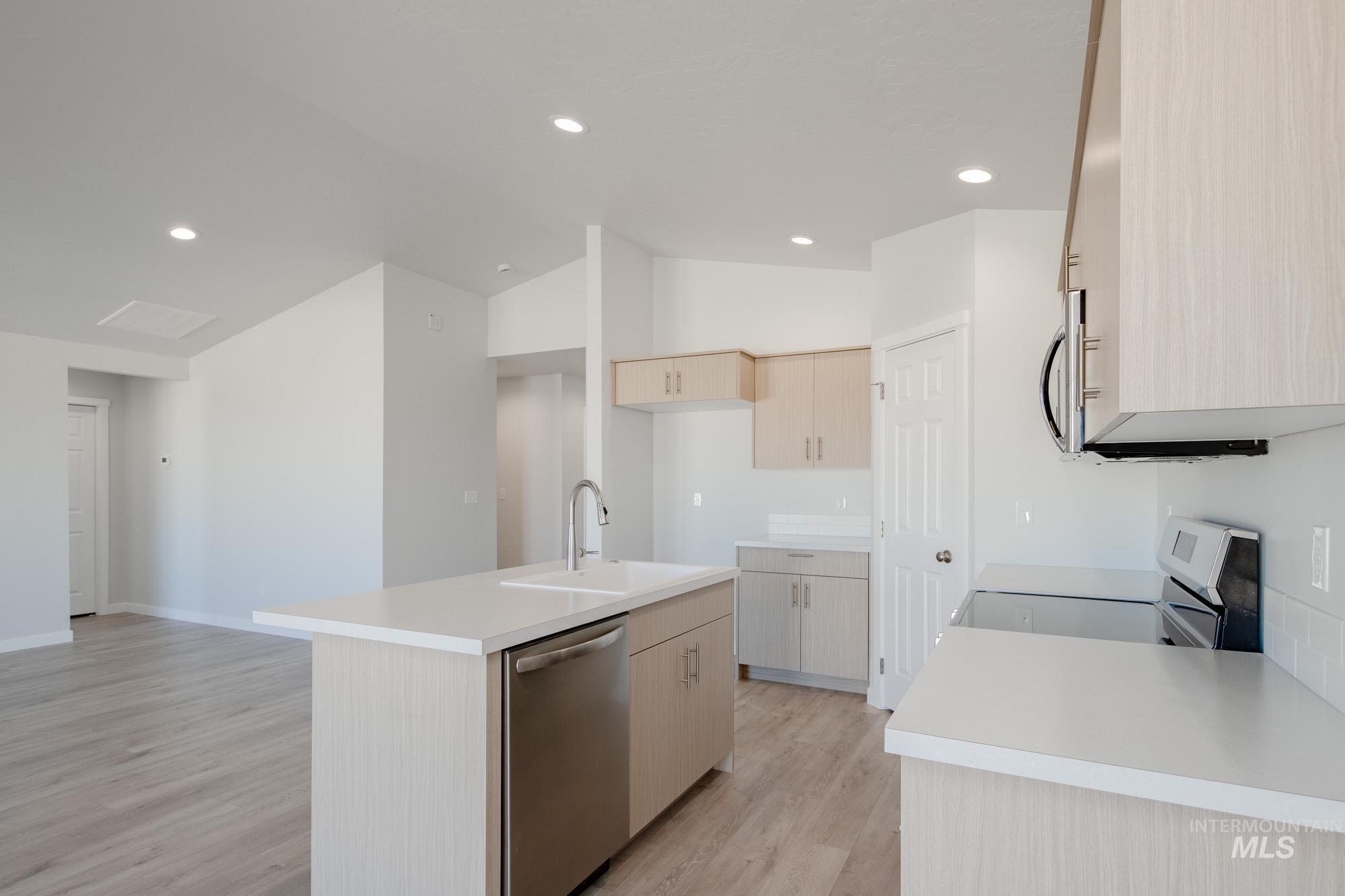 1832 West Unforgettable Street Meridian, ID 83642 - Photo 8 of 22 Kitchen with light brown cabinets, light countertops, appliances with stainless steel finishes, a kitchen island with sink, and light wood finished floors