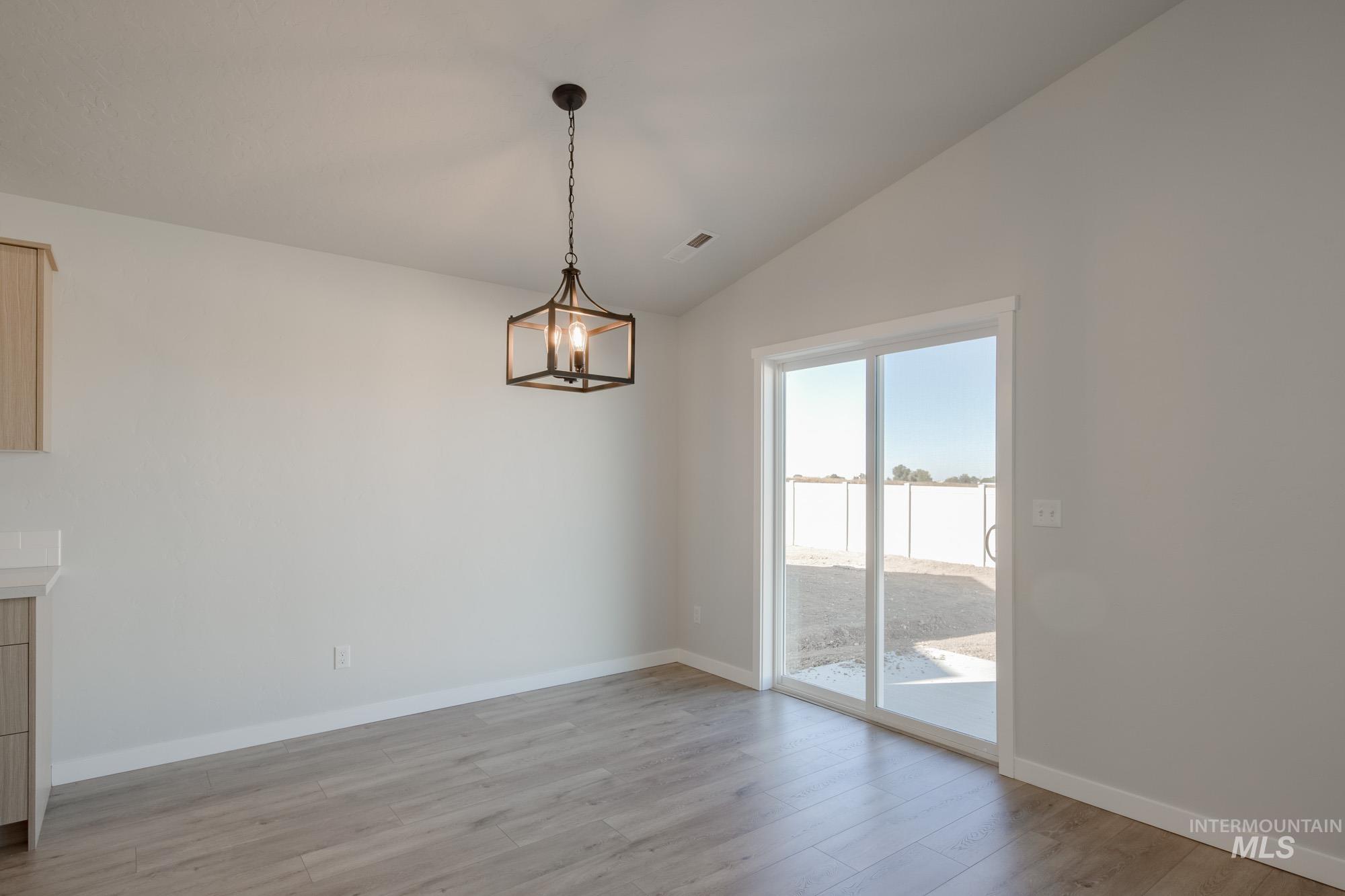 1832 West Unforgettable Street Meridian, ID 83642 - Photo 9 of 22 Unfurnished dining area with light wood-type flooring, lofted ceiling, and a chandelier