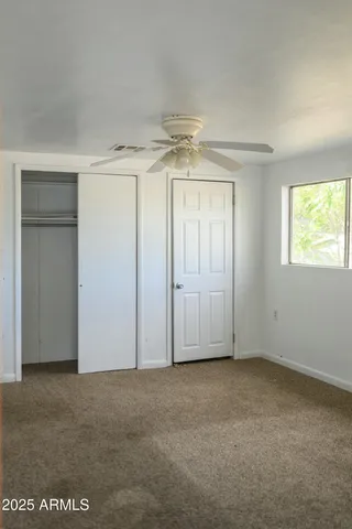 an empty room with windows and fan