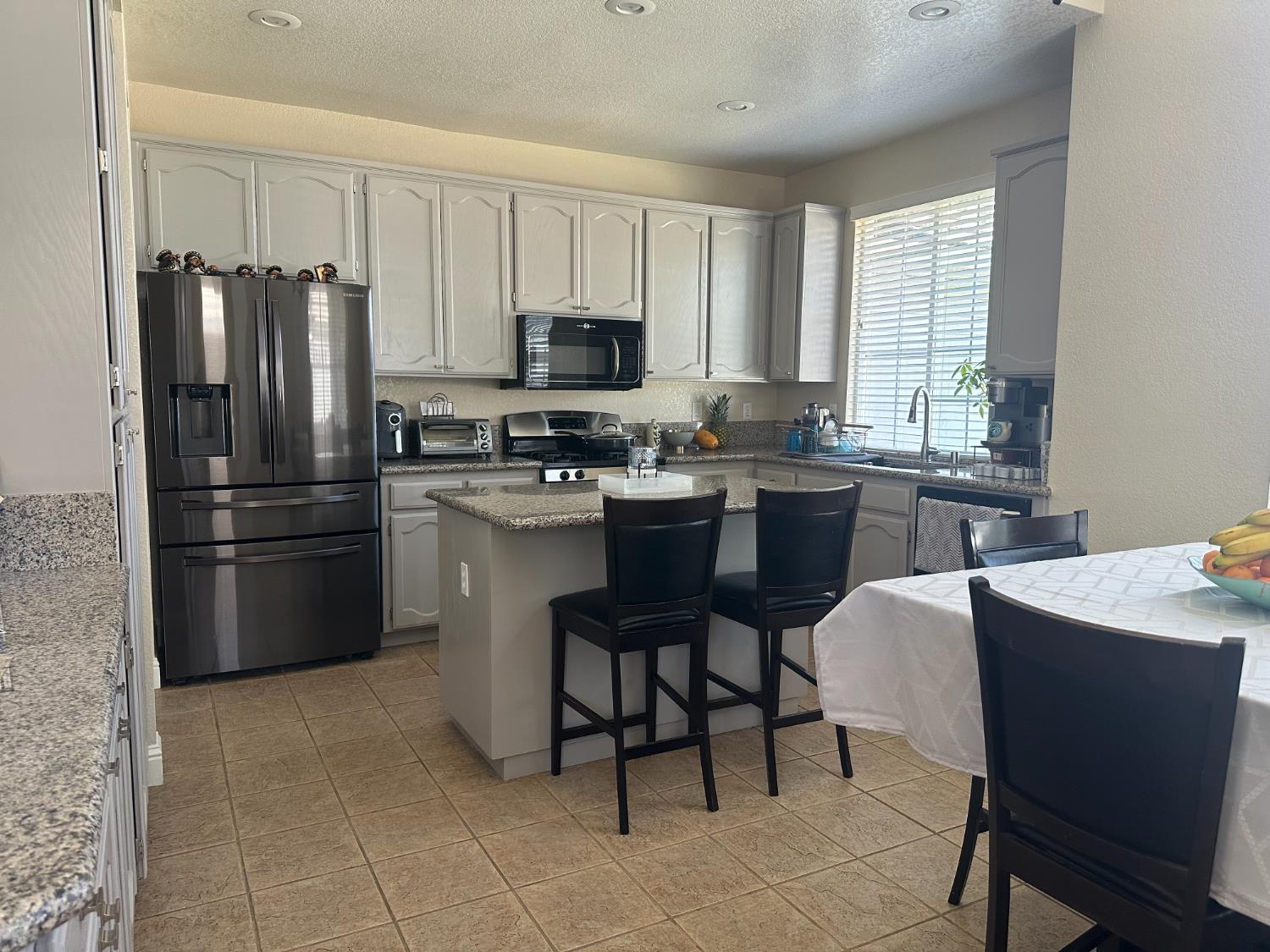 628 Mission Ridge Drive Manteca, CA 95337 - Photo 11 of 27 a kitchen with stainless steel appliances granite countertop a refrigerator a sink a stove a dining table and chairs