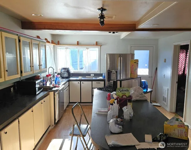 a kitchen with stainless steel appliances granite countertop a refrigerator dining table and chairs