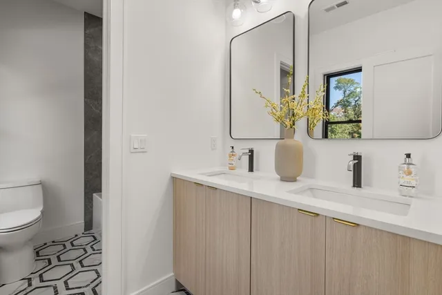 a bathroom with a granite countertop sink mirror and toilet