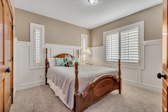 896 West 675 South Mapleton, UT 84664 - Photo 26 of 77 Bedroom with wainscoting, multiple windows, light colored carpet, and a decorative wall