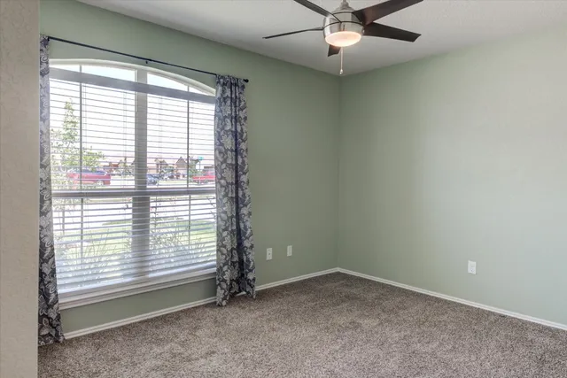 an empty room with a window and a fan