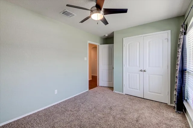 an empty room with closet and a chandelier fan
