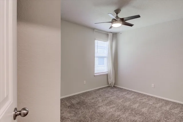 an empty room with a window and a fan