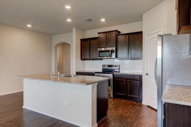 a kitchen with kitchen island granite countertop stainless steel appliances and wooden cabinets
