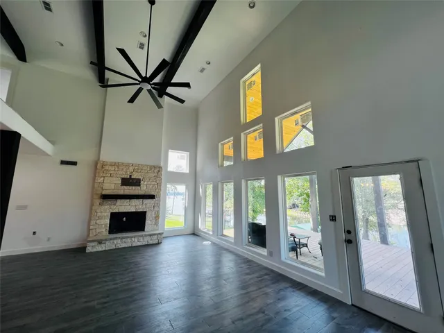 a view of a livingroom with a fireplace a ceiling fan and wooden floor