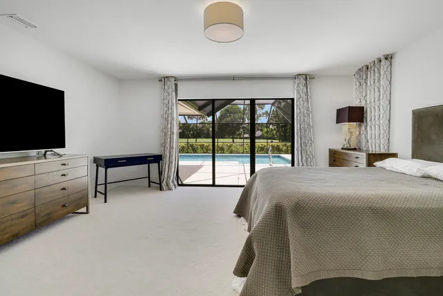 a bedroom with a bed and flat tv screen on the dresser