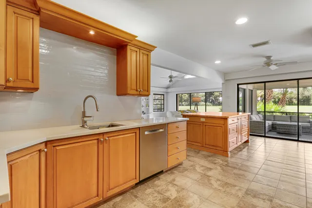 a large kitchen with stainless steel appliances wooden cabinets a sink and a large window