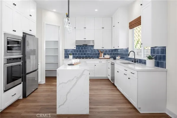 a large kitchen with stainless steel appliances a large counter top a stove a refrigerator and a window