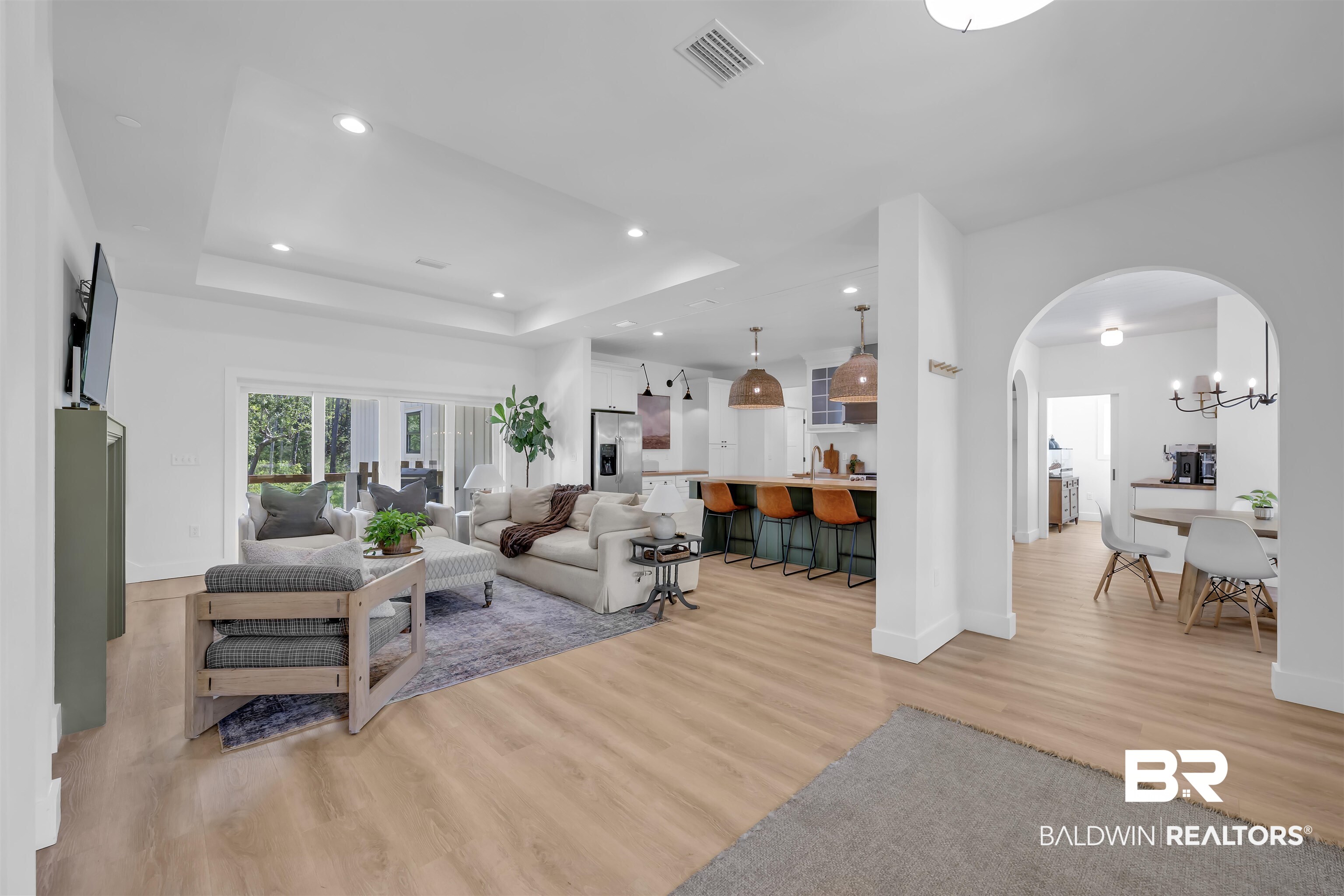 19058 James Road Gulf Shores, AL 36542 - Photo 7 of 49 Living room featuring light wood finished floors, arched walkways, recessed lighting, and a raised ceiling