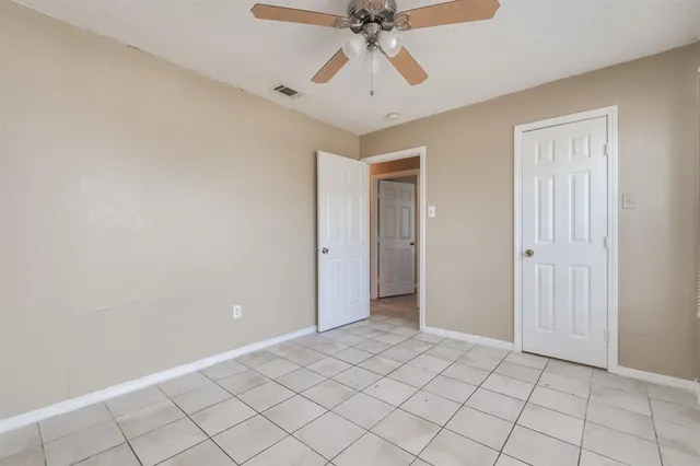 a view of an empty room and chandelier fan