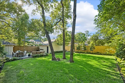 a view of a patio with table and chairs potted plants and a large tree