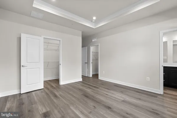 a view of an empty room with wooden floor and closet