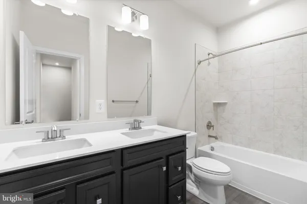 a bathroom with a double vanity sink toilet mirror and bathtub