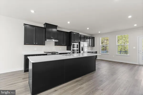 a kitchen with stainless steel appliances granite countertop a stove a sink and a microwave