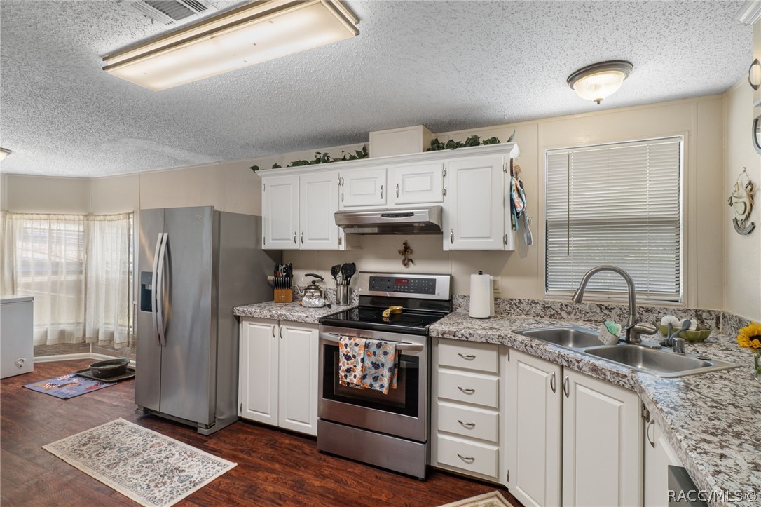 7927 West Cyprian Court Homosassa, FL 34448 - Photo 12 of 40 a kitchen with stainless steel appliances granite countertop a stove a sink dishwasher a refrigerator and white cabinets with wooden floor
