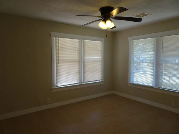 an empty room with a window and a fan