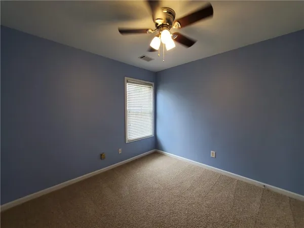 an empty room with a chandelier fan and windows