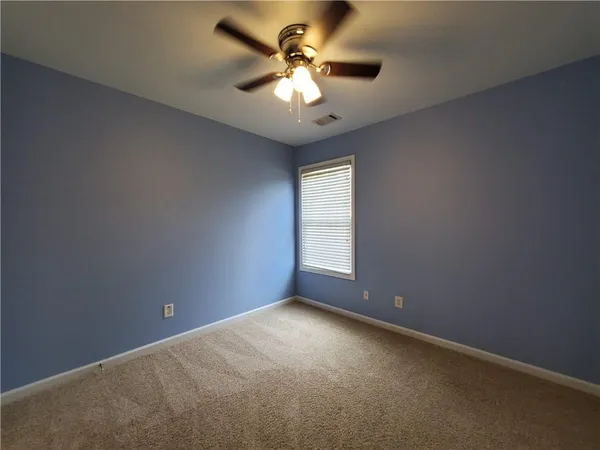 an empty room with a chandelier fan and windows