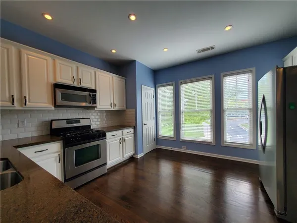 a kitchen with stainless steel appliances granite countertop a stove a sink and a microwave
