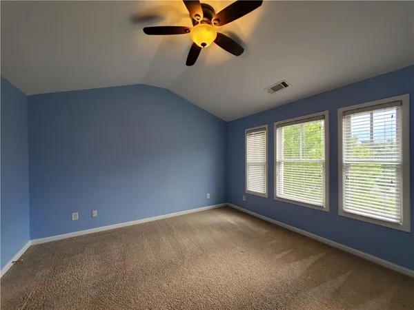 a view of an empty room with window and a kitchen
