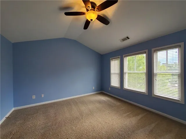 a view of an empty room with window and a kitchen