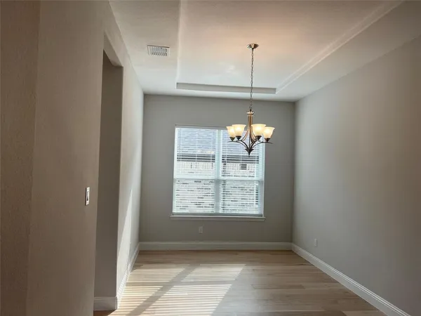 an empty room with chandelier fan and windows
