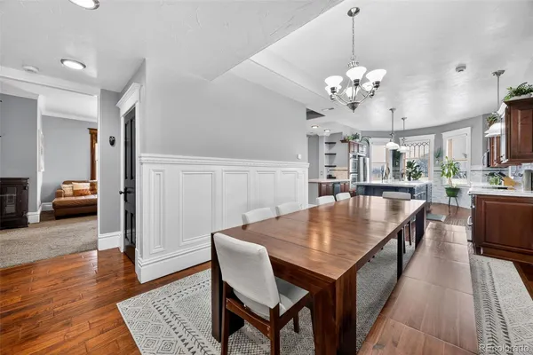 a dining room with wooden floor a chandelier a wooden table and chairs
