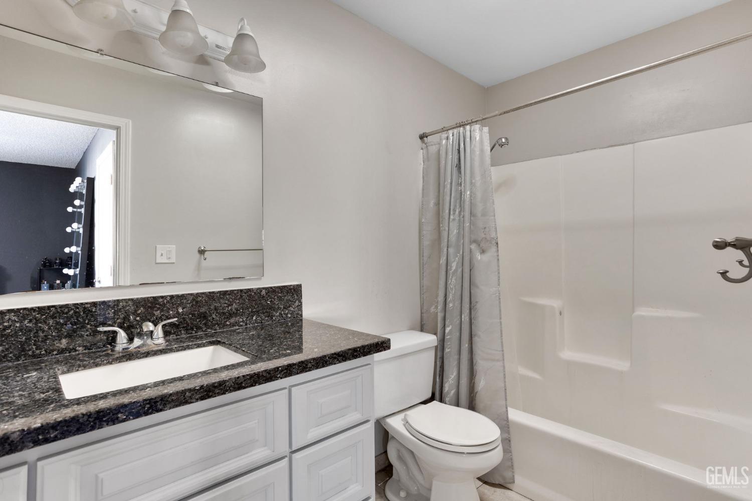 Undisclosed Address Bakersfield, CA 93307 - Photo 27 of 42 a bathroom with a granite countertop sink a toilet a mirror and shower