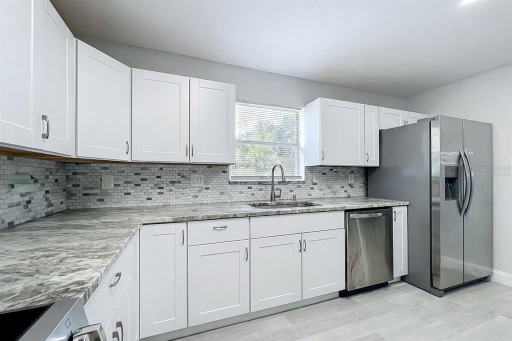 12368 Killian Street Spring Hill, FL 34609 - Photo 11 of 25 a kitchen with granite countertop white cabinets white appliances and sink