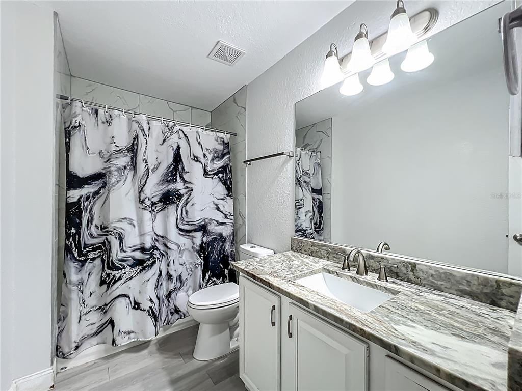 12368 Killian Street Spring Hill, FL 34609 - Photo 19 of 25 a bathroom with a granite countertop sink a toilet and a mirror