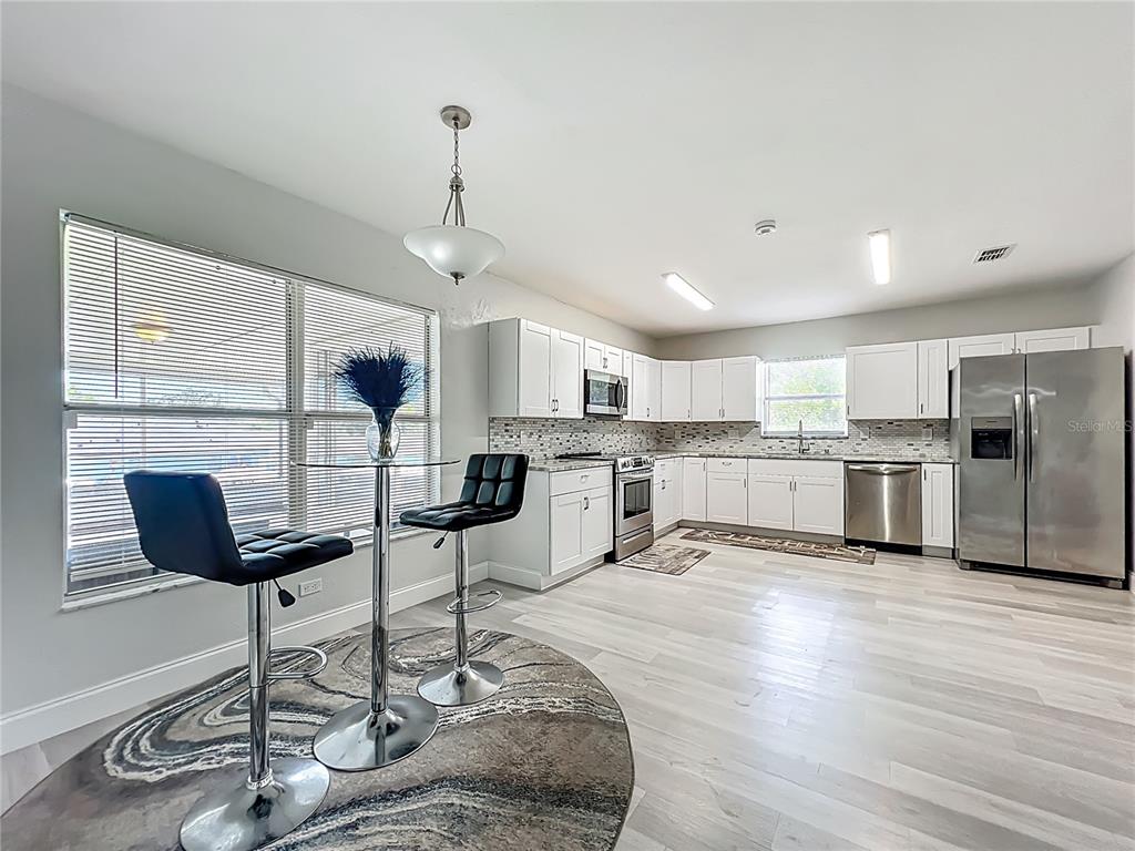 12368 Killian Street Spring Hill, FL 34609 - Photo 8 of 25 a kitchen with stainless steel appliances kitchen island granite countertop a stove a refrigerator and white cabinets with wooden floor