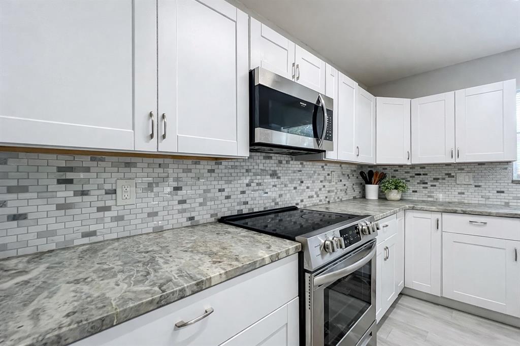 12368 Killian Street Spring Hill, FL 34609 - Photo 10 of 25 a kitchen with granite countertop white cabinets stainless steel appliances and a sink