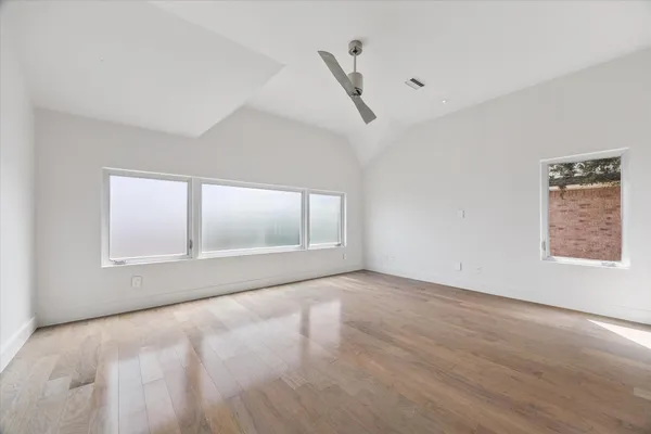 a view of an empty room with a window and wooden floor