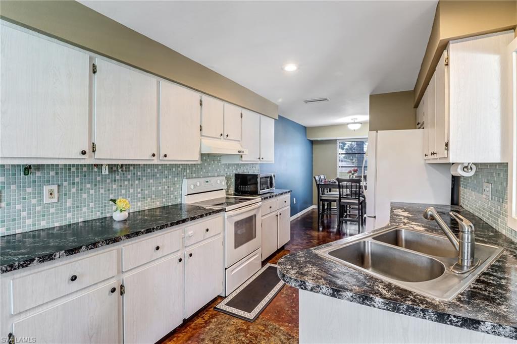 103 Doral Circle Naples, FL 34113 - Photo 11 of 25 a kitchen with granite countertop a sink a stove and cabinets