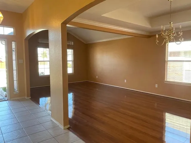 a view of a hallway with wooden floor and a chandelier