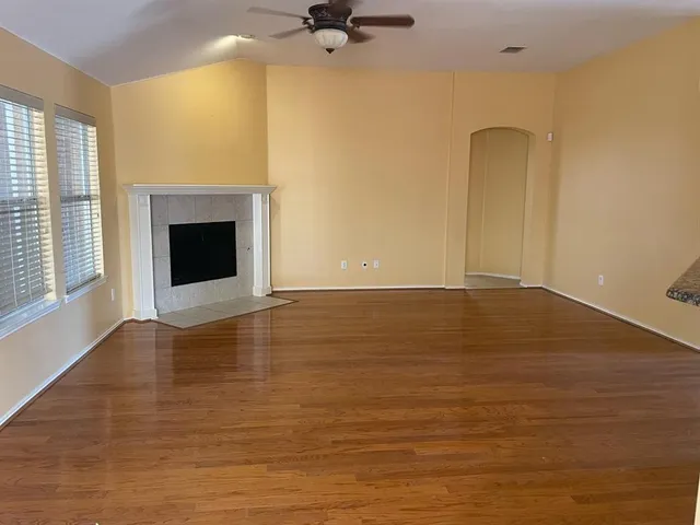 a view of an empty room with glass door and wooden floor