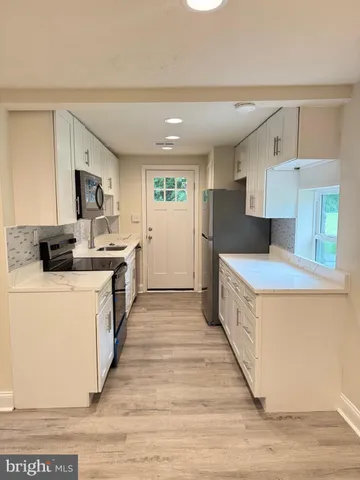 a large kitchen with stainless steel appliances a stove a sink dishwasher and a refrigerator