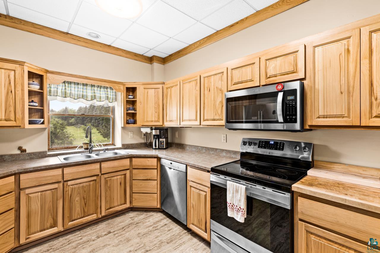 4800 Tower Road Moose Lake, MN 55767 - Photo 57 of 83 Kitchen featuring wood cabinetry, stainless steel appliances, a double basin sink, ample counter space, and durable flooring