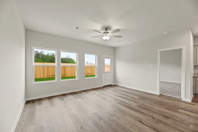 a view of an empty room with a window and wooden floor
