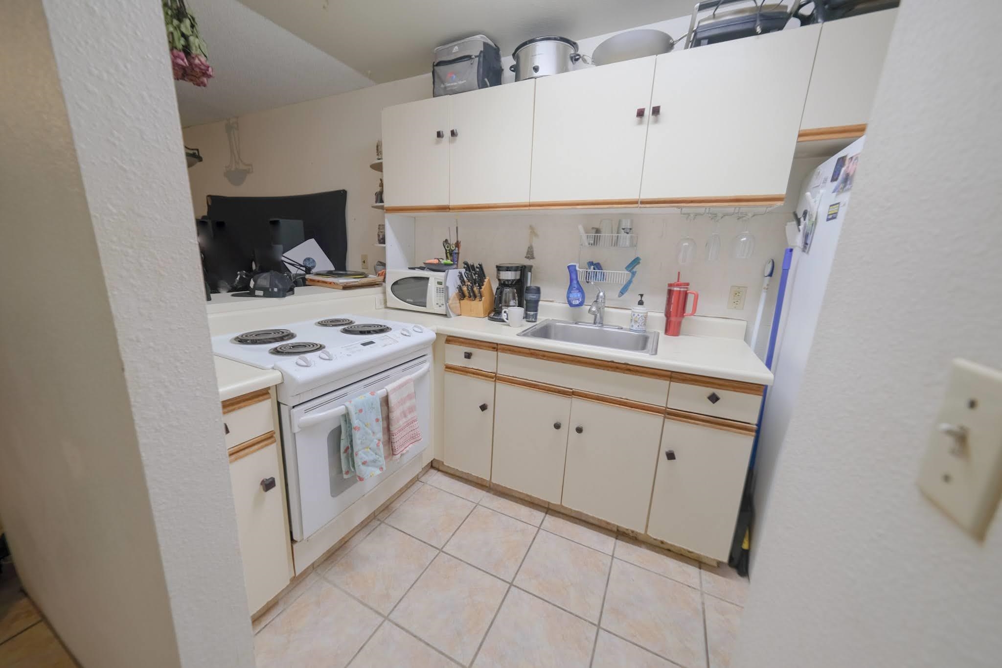 160 Keonekai Road, Unit 13206 Kihei, HI 96753 - Photo 6 of 14 a kitchen with cabinets and white appliances