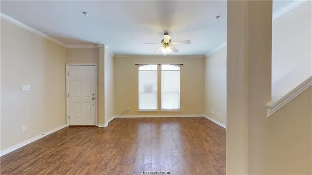 a view of an empty room with a window and wooden floor