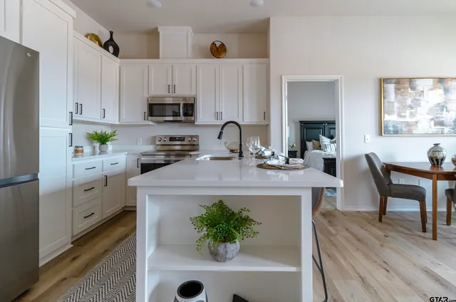 a kitchen with stainless steel appliances a stove a refrigerator a white table and chairs