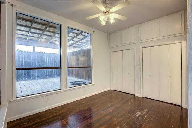 a view of empty room with wooden floor and fan